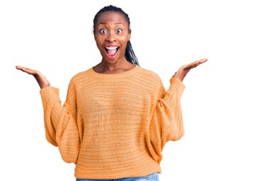 Genç Afro-Amerikalı kadın gündelik giysiler giyip çılgınlığı kutluyor ve başarıya hayret ediyor. Kolları açık, gözleri açık heyecanla haykırıyor. Kazanan konsept 