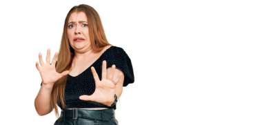 Genç, güzel, kızıl saçlı, zarif kıyafetler giyen, tiksindirici bir ifade takınan, tiksindirici, tiksindirici bir yüz ifadesi olan bir kadın. Eller havada. 