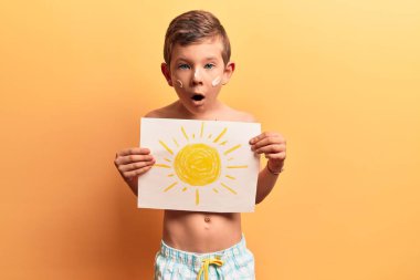 Mayo ve yaz şapkası takan tatlı sarışın çocuk şaşırmak için ağzı açık kalmış, korkmuş ve şaşkına dönmüş, inançsız yüz. 