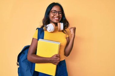Öğrenci çantası ve kitapları tutan genç Hintli kız gururla bağırıyor, zaferi ve başarıyı kutluyor. 