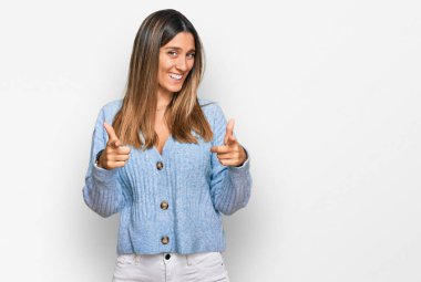 Günlük kıyafetler giymiş genç bir kadın mutlu ve komik yüzüyle kamerayı işaret ediyor. iyi enerji ve titreşimler. 