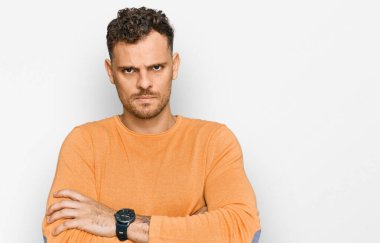 Gündelik kıyafetler giyen, kuşkucu ve gergin genç İspanyol bir adam. Yüzünde çapraz kollarla onaylamayan bir ifade var. negatif kişi. 