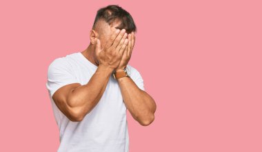 Yakışıklı, beyaz tişört giyen, suratını ellerle örten ve ağlayan kaslı adam. depresyon kavramı. 