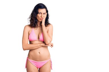 Bikini giyen genç ve güzel bir İspanyol kadın kollarını kavuşturarak depresyondan sıkılmış ve yorgun görünüyor.. 