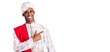 Gelenek giyinmiş Afrikalı yakışıklı bir adam Sherwani sari, neşeli, yüzünde bir gülümseme, mutlu ve doğal bir ifadeyle elleri ve parmakları kenarda gösteren. 