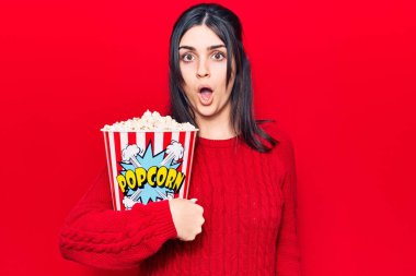 Genç ve güzel bir kız patlamış mısır yiyor. Korkmuş ve ağzı açık, şaşırmış ve şaşırmış. 