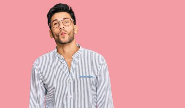 Gündelik kıyafetler ve gözlük takan genç yakışıklı adam dudaklarıyla balık suratı yapıyor, çılgınca ve komik bir jest. Komik ifade. 