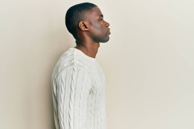 Afro-Amerikalı genç bir adam günlük giysiler giymiş, rahat bir görünüm takınıyor, doğal bir yüzü ve kendine güvenen bir gülümsemesi var.. 