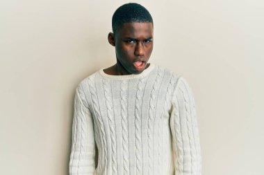 Şok olmuş gibi giyinmiş, kuşkucu ve iğneleyici bakışları olan, ağzı açık kalmış genç Afro-Amerikan bir adam. 