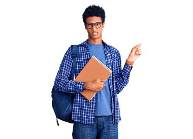 Afrika kökenli Amerikalı genç bir adam sırt çantası takıyor. Elinde kitap var. Endişeli ve endişeli. 