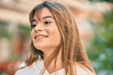 Beyaz, sportif, genç bir kız şehirde mutlu mesut dikiliyor..