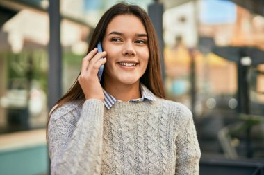 Genç İspanyol kız gülümsüyor. Şehirdeki akıllı telefondan konuşuyor..