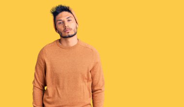 Kış süveteri ve yün şapka giyen yakışıklı Latin Amerikalı genç adam yüzünde ciddi bir ifadeyle rahatlamış. Basit ve doğal bir şekilde kameraya bakıyorsun.. 