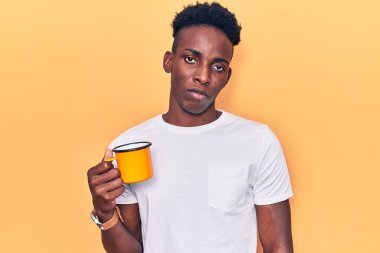 Genç Afro-Amerikalı bir adam elinde kahve tutarken düşünceli ve ayık bir ifade takınırken kendinden emin görünüyor. 