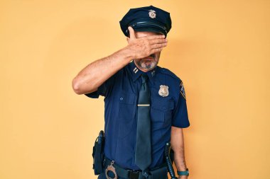 Orta yaşlı İspanyol polis üniforması giyen, gözlerini kapayan, ciddi ve üzgün görünen bir adam. Görme, saklama ve reddetme konsepti 