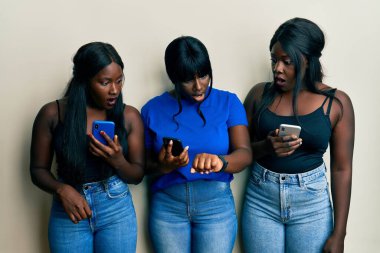 Üç Afrikalı Amerikalı genç arkadaş akıllı telefon kullanıyor. Saate bakıyorlar. Endişeli ve geç kalmaktan korkuyorlar. 