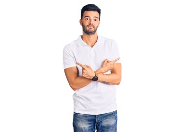 Gündelik kıyafetler giyen genç, yakışıklı İspanyol adam her iki tarafı da parmaklarıyla işaret ediyor. Farklı yönlerden. 