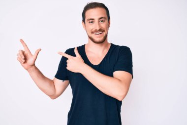 Gündelik kıyafetler giyen, gülümseyen ve kameraya bakan genç, yakışıklı bir adam.. 