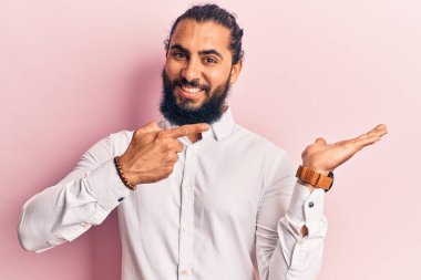 Gündelik giysiler giyen genç Arap adam kameraya hayret ediyor ve gülümsüyor.. 