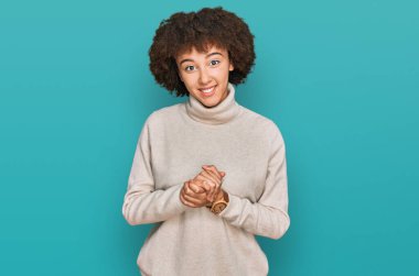 Elleri birbirinin üzerine yün kazak giyen ve gülümseyen, gevşemiş ve neşeli parmakları çaprazlayan genç İspanyol kız. Başarı ve iyimserlik 