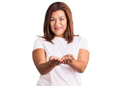 Gri arka planda beyaz tişörtlü ve siyah elbiseli güzel bir kadın.