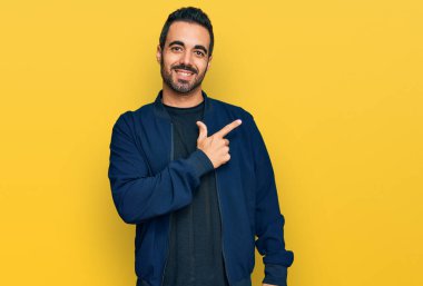 Yüzünde mutlu ve doğal bir ifade olan, elleri ve parmaklarıyla işaret eden, güler yüzlü, gündelik kıyafetler giyen genç İspanyol adam. 