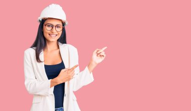 Mimar şapkalı, gözlüklü, gülümseyen ve kameraya bakan genç ve güzel bir Latin kız.. 