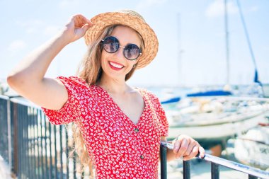 Genç sarışın kadın tatilde gülümsüyor. Mutlu bir şekilde caddede yürüyor.