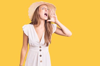 Yazlık elbise ve şapka giyen, el ele tutuşup bağıran genç, güzel sarışın kadın. iletişim konsepti. 