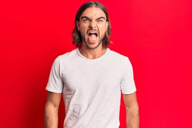 Sıradan kıyafetler giyen genç yakışıklı bir adam komik bir ifadeyle dilini dışarı çıkartıyor. duygu kavramı. 