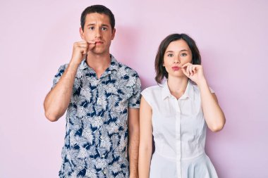 Gündelik kıyafetler giyen güzel bir çift ağızları ve dudakları parmaklarıyla fermuar gibi kapalı. gizli ve sessiz, tabu konuşması 