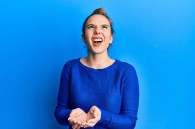 Sarışın genç bir kadın el ele tutuşmuş, konsepte kızgın ve kızgın bir çığlık atıyor sinirli ve öfkeli, öfkeyle bağırıyor.. 