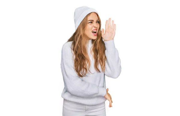 ウールのセーターと冬の帽子を身に着けている若い白人の女の子は大声で叫び 口の中で手で横に叫んでいます コミュニケーションの概念 — ストック写真