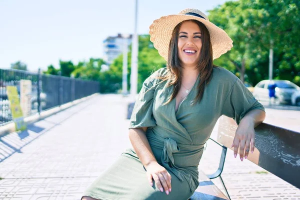 Genç İspanyol kadın tatilde gülümsüyor. Mutlu bir şekilde şehrin sokaklarında bankta oturuyor.