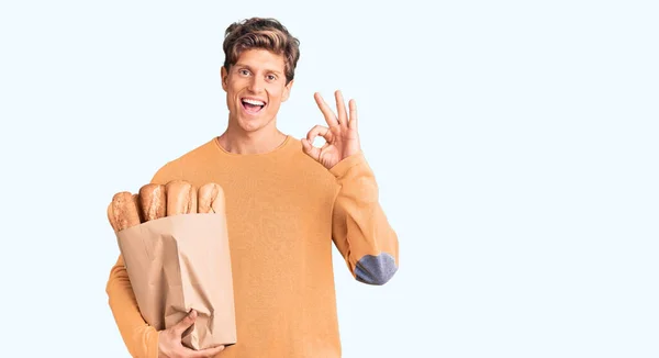 Jovem Homem Bonito Segurando Saco Papel Com Pão Fazendo Sinal — Fotografia de Stock