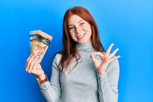 Kanada Doları Tutan Genç Kızıl Saçlı Kız Parmaklarıyla Imza Atıyor — Stok fotoğraf