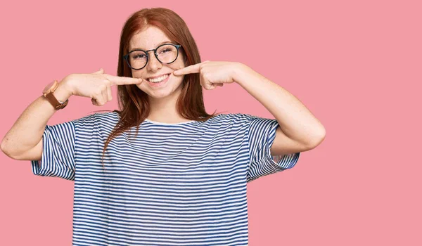 若い読み頭の女性が陽気な表情と指の歯と口で指して笑顔カジュアルな服や眼鏡を着て 歯の健康の概念 — ストック写真