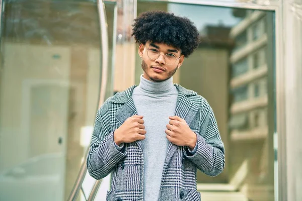 Genç Afro-Amerikan iş adamı ciddi bir ifadeyle şehirde duruyor..