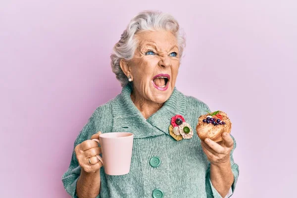 Yaşlı Gri Saçlı Kadın Bir Fincan Kahve Içip Çörek Yiyor — Stok fotoğraf