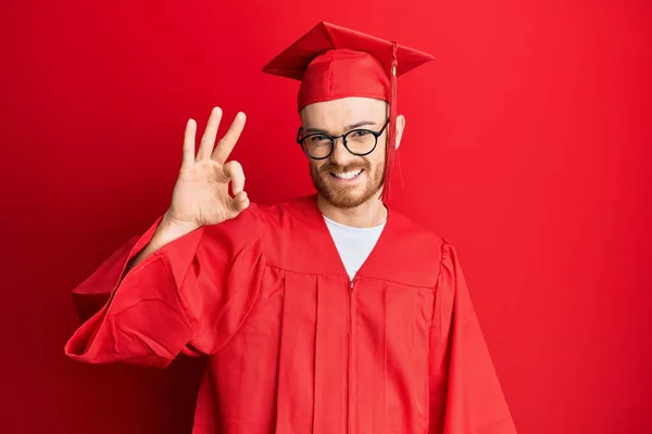 Homem Ruivo Jovem Vestindo Chapéu Formatura Vermelho Roupão Cerimônia Sorrindo — Fotografia de Stock