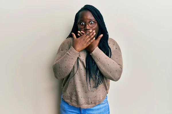 カジュアルな服と眼鏡を身に着けている編組と若い黒人女性は間違いのために手で口をカバーショックを受けた 秘密の概念 — ストック写真
