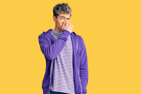 Young Handsome Man Wearing Casual Purple Sweatshirt Smelling Something Stinky — Stock Photo, Image