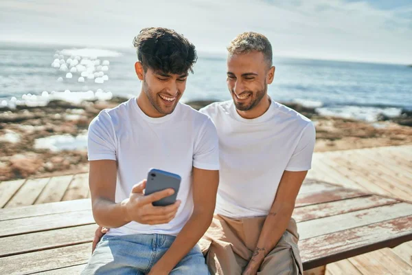 Νεαρό Γκέι Ζευγάρι Χαμογελά Χαρούμενος Χρησιμοποιώντας Smartphone Στην Παραλία — Φωτογραφία Αρχείου