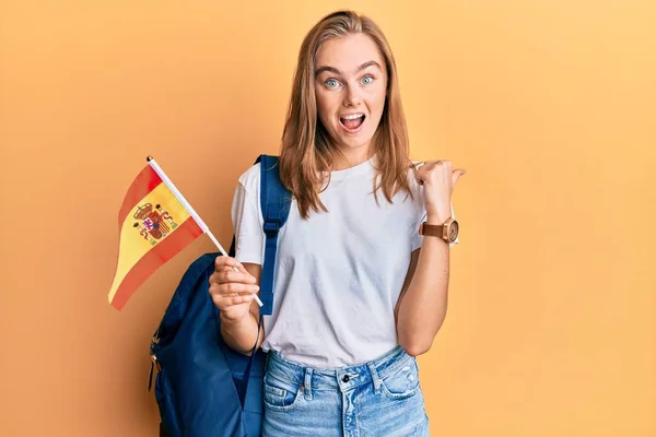 Hermosa Mujer Rubia Estudiante Intercambio Sosteniendo Bandera Española Señalando Pulgar —  Fotos de Stock