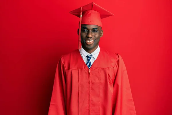 卒業キャップと式用のローブを身に着けている若いアフリカ系アメリカ人男性は 顔に幸せとクールな笑顔で 運のいい人 — ストック写真