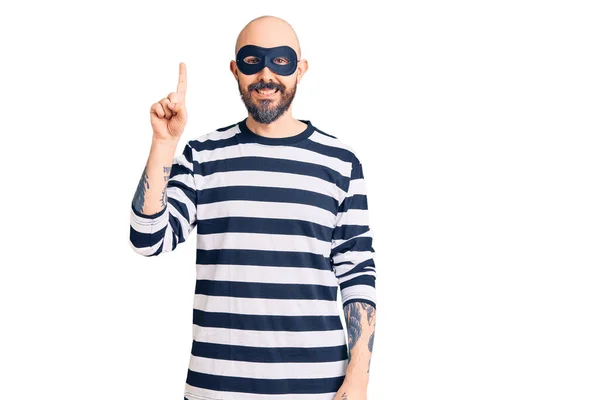 Junger Gutaussehender Mann Mit Einbrechermaske Zeigt Mit Finger Nummer Eins — Stockfoto