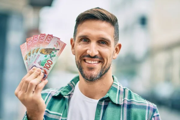 Joven Hombre Caucásico Sonriendo Feliz Pie Sosteniendo Nuevos Billetes Zealand —  Fotos de Stock