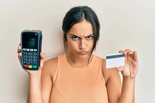 Młoda Brunetka Trzymająca Dataphone Kartę Kredytową Sceptyczna Nerwowa Marszcząca Brwi — Zdjęcie stockowe