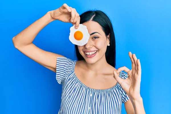Piękna Młoda Kobieta Trzyma Smażone Jajko Robi Znak Palcami Uśmiechając — Zdjęcie stockowe