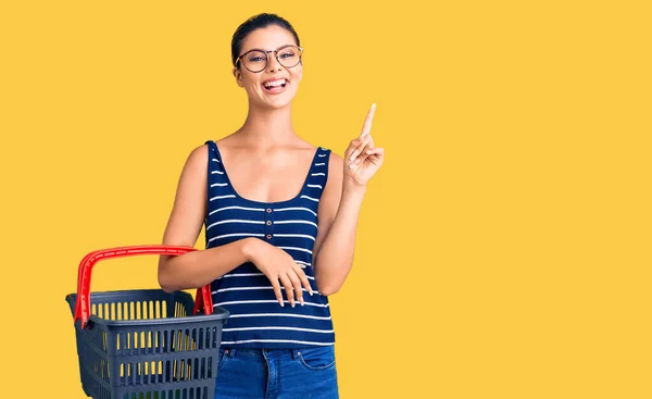 Jovem Mulher Bonita Segurando Supermercado Cesta Compras Surpreso Com Uma — Fotografia de Stock